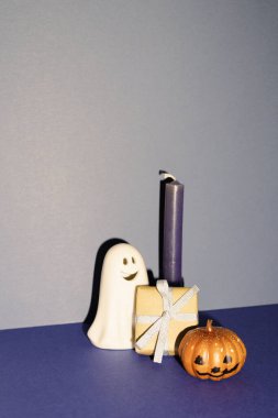 Cadılar Bayramı partisi dekoru, hayalet ve balkabağı, hediye kutusu, mavi arka planda mum.