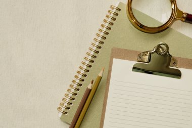 Yeşil defter, dosya, renkli kalemler, masanın üzerinde büyüteç. düz alan, üst görünüm, kopyala boşluk