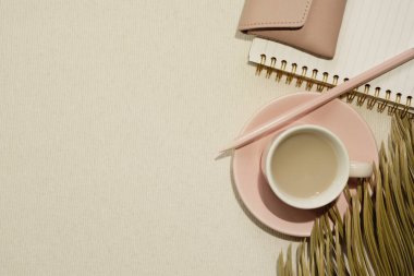 Pembe malzemeler. Bir fincan kahve ve defter, renkli kalem, bej kumaş arka planda bir kese. düz alan, üst görünüm, kopyala boşluk