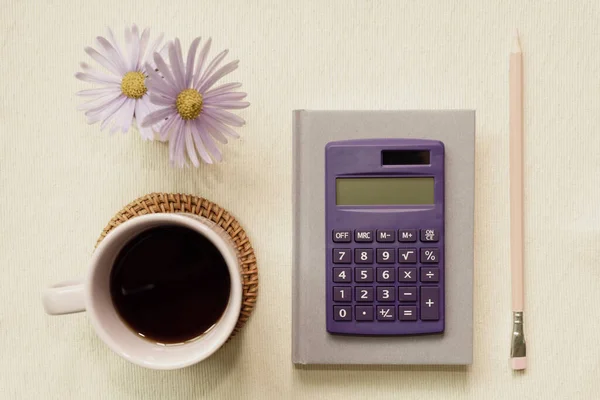 Purple supplies. notebook, calculator, colored pencil, cup of coffee, flower on desk. flat lay, top view