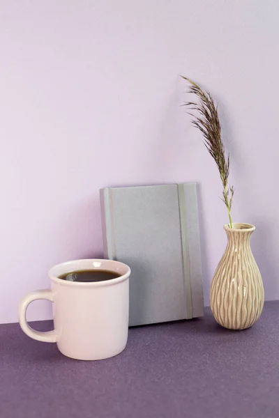 Purple notebook and cup of coffee, plant on desk. workspace