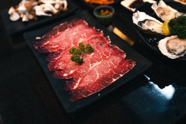 Lokantada siyah bir tabakta dilimlenmiş Shabu eti, Japon Dilimlenmiş Bifteği.