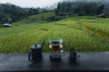 Açık hava kahve makinesi ahşap masa pirinç tarlası arka planında.