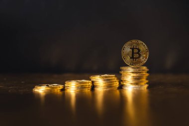 Siyah altın zemin üzerine istiflenmiş bitcoin paraları