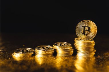 Siyah altın zemin üzerine istiflenmiş bitcoin paraları