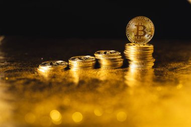 Siyah altın zemin üzerine istiflenmiş bitcoin paraları