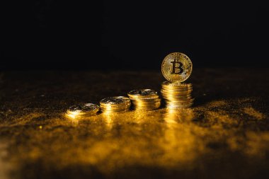 Siyah altın zemin üzerine istiflenmiş bitcoin paraları