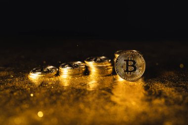 Siyah altın zemin üzerine istiflenmiş bitcoin paraları
