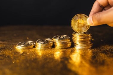 Siyah altın zemin üzerine istiflenmiş bitcoin paraları