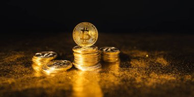 Siyah altın zemin üzerine istiflenmiş bitcoin paraları
