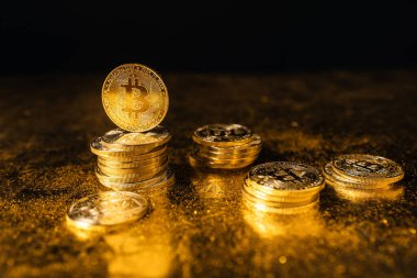 Siyah altın zemin üzerine istiflenmiş bitcoin paraları