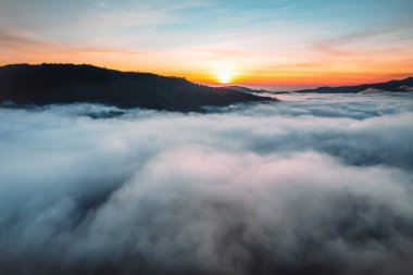 Bulutların üzerinde uçuyor güneş doğuyor ve sis tepede