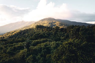 Gün batımında dağların üzerinden bulutlar yükselir.