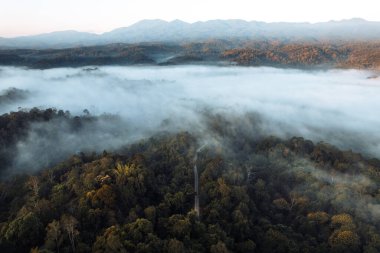 Bulutların üzerinde uçuyor güneş doğuyor ve sis tepede