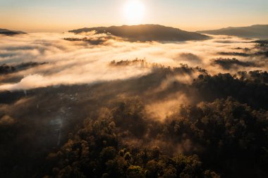 Bulutların üzerinde uçuyor güneş doğuyor ve sis tepede