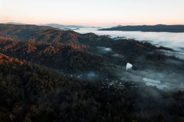 Bulutların üzerinde uçuyor güneş doğuyor ve sis tepede
