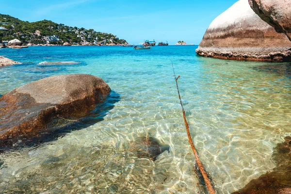 View of the bay and rocks on the island and the boats in the clear waters of Koh Tao.