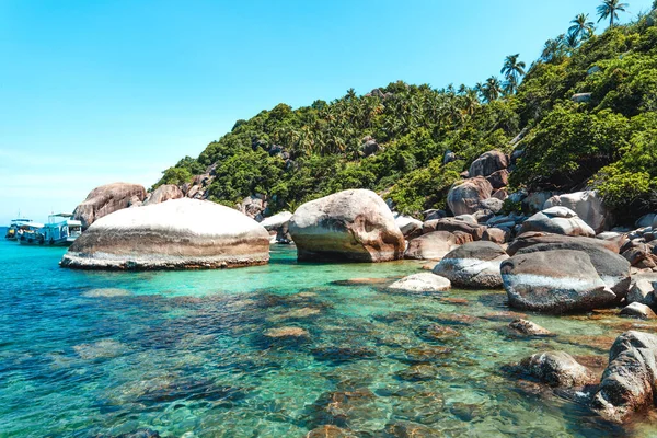 View of the bay and rocks on the island and the boats in the clear waters of Koh Tao.