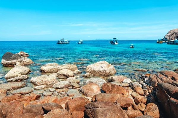 View of the bay and rocks on the island and the boats in the clear waters of Koh Tao.