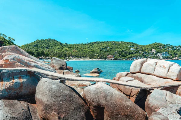 View of the bay and rocks on the island and the boats in the clear waters of Koh Tao.