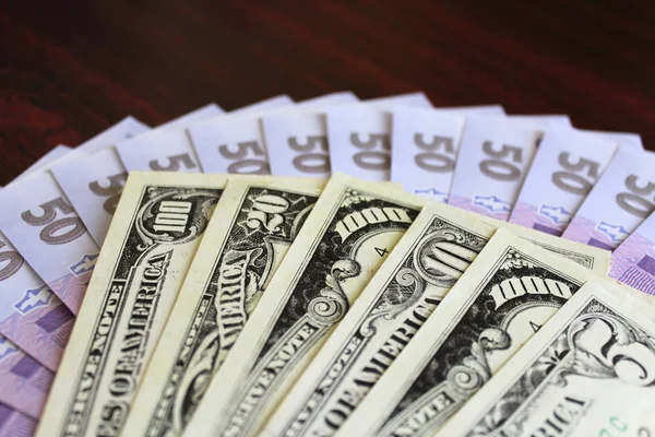 Billetes de dólar y grivnas aislados sobre fondo oscuro — Foto de Stock