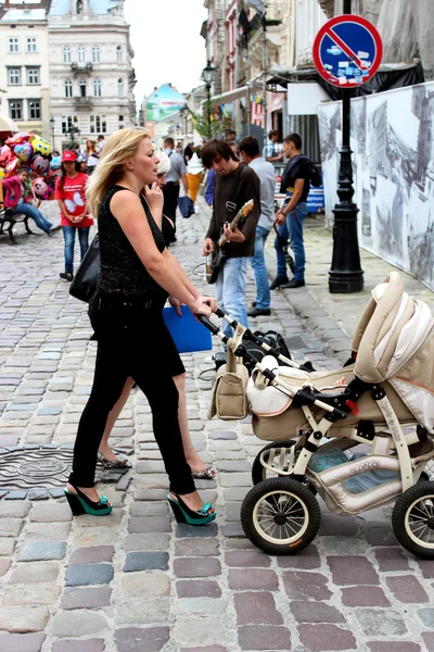 Mãe com perambulador andando ao longo da rua — Fotografia de Stock