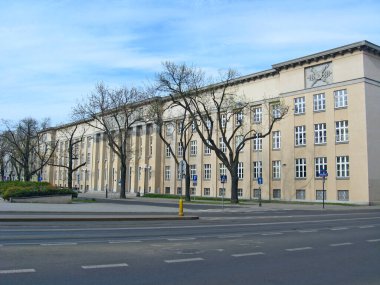 Lodz - Polonya. 22 Temmuz 2019: Lodz 'da modern mimari. Caddenin karşısındaki yaya güzel bir binayla karşıdan karşıya geçiyor. Trafik ışıkları olan boş bir cadde. Trafik ışıkları ve kaldırımlar. Şehir sokağı
