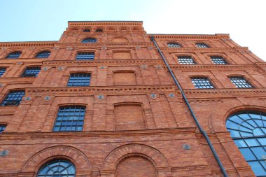Lodz - Polonya. 17 Ağustos 2019: Eski tuğla bina cephesi. Polonya 'nın Lodz şehrinde pencereleri olan eski bir fabrika binası. Polonya 'da eski mimari. Kırmızı tuğla fabrikası cephesi