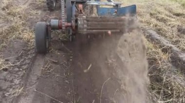 Tractor with potato harvester on field. view of potato harvester. Process of digging potatoes vegetable in field on soil. tractor harvesting potato on plantation. Digging up potato crop. Potato digger