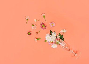 Cennetin pembe arka planında çeşitli çiçekler ve şampanya kadehleri olan yaratıcı, asgari düzlem. Anneler Günü ya da Sevgililer Günü 'nün geçmiş tasarımı. Bahar minimum konsepti.