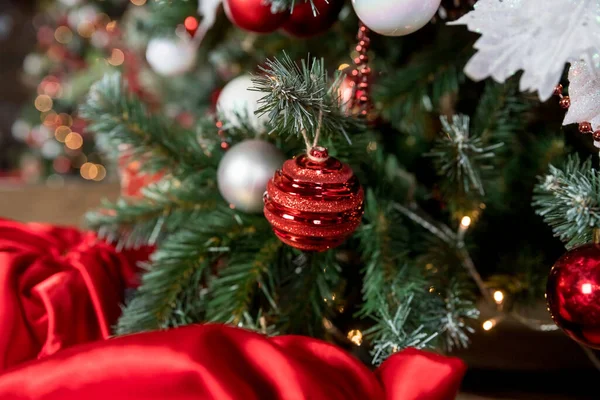 Primo piano di bagattelle bianche e rosse appese a un ramo di Natale decorato. sfondo astratto con luci sfocate.Camera decorata per il nuovo anno e Natale. — Foto Stock