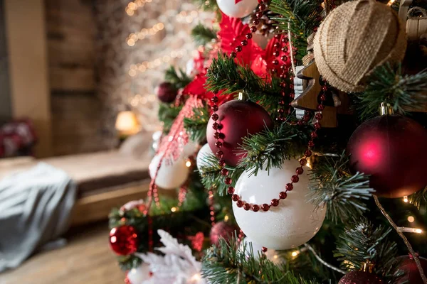Крупный план красной и белой безделушки, висящей на украшенной рождественской ветке. комната, оформленная в новогоднем и рождественском стиле. — стоковое фото