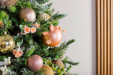 Beyaz, bronz, pembe topları, kar ve ışıldayan çelengi olan lüks Noel ağacı. Toplu ve dekorlu yeni yıl kompozisyonu. Süslü bir odada çeşitli süsleri olan zarif bir ağaç.