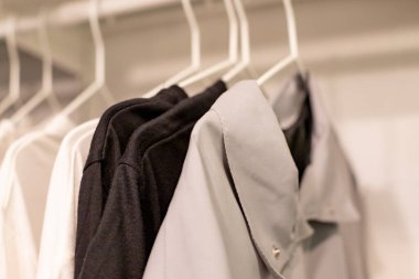 Gardıroptaki korkuluklarda giysiler. Kolay giyinmek için sezonluk kapsül, bir şeyler sipariş etmek, temizlik. Renkli günlük kıyafetler askılar, elbise ve ayakkabılarla dolu soyunma odası. depolama