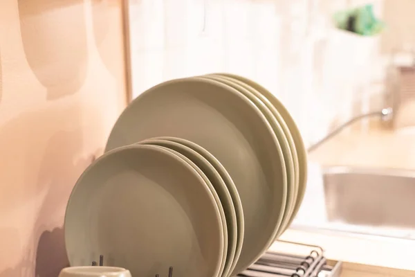 Mutfakta tabaklar için, yeni tasarımlar için modern mutfakta sofra takımı kurutmak için. Mutfak dolabındaki metal raflarda seramik tabaklar ve bardaklar. — Stok fotoğraf