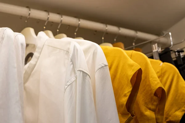 Clothes on a rail in a wardrobe. Seasonal capsule for easy dressing, order in things, cleaning out.Colorful casual clothes hang on hangers.Wardrobe, dressing room filled with clothes, shoes. storage — Stock Photo, Image