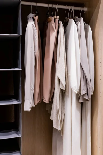 Κρεμάστρες με διαφορετικά ρούχα στην ντουλάπα ντουλάπα.πουκάμισα και φόρεμα κρέμεται σε ράγα σε ξύλινη ντουλάπα στο σπίτι.μπουτίκ ρούχων — Φωτογραφία Αρχείου