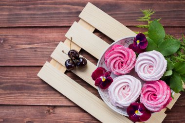 Yenmeye hazır çileklerle kaplı bir tabağın yakın çekimi. Kirazlı el yapımı marşmelov, ahşap arka plan. Pembe, beyaz lokum, Meringue, Zephyr Seçici Odaklanma