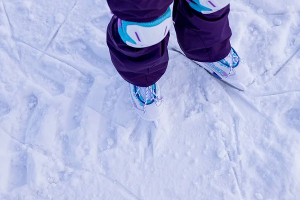 Holčička v zimním oblečení s ochranou bruslení na kluzišti. učení, trénink, první lekce o ledu. zimní aktivity — Stock fotografie