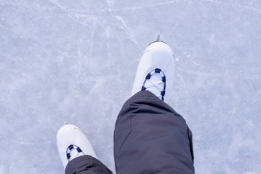 Arkaplandaki artistik patenlerin yakın plan görüntüleri. Kışın aile ile buz pateni aktiviteleri. Buz pateni pistinde başlayan buz patenci bacakları, yukarıdan görüş.