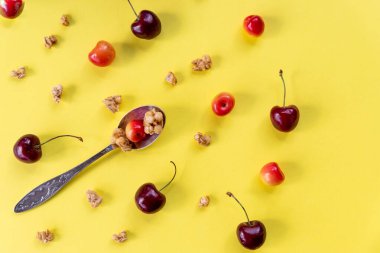 Sağlıklı organik vejetaryen kahvaltısı, kaşık ve müsli üzerine taze çilek ve parlak arka planda kiraz. Yazdan önce diyet. Çıtır müsli kahvaltı için iyidir.