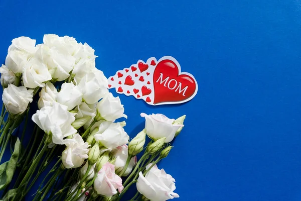 Biglietto di auguri per la Festa della Mamma con fiori primaverili e cuore decorativo su sfondo blu. Composizione floreale, Biglietto di auguri.. — Foto Stock