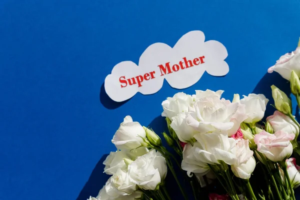 Buona festa della mamma biglietto di auguri con fiori primaverili e cuore decorativo su sfondo blu. composizione floreale, biglietto di auguri super Madre — Foto Stock