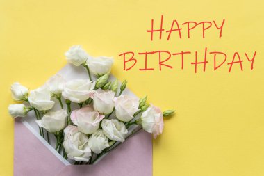 Şık bir doğum günü tebrik kartı tasarımı. Sarı arkaplan üzerine Mutlu Yıllar mesajı at. Beyaz Eustoma çiçekleri zarfın içinde. Moda düzlüğü.