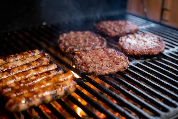 Dymne mięso z hamburgerów grillujące hamburgery. Smażyć na otwartym ogniu na grillu - bbq.Burgery i kiełbasy Gotowanie nad płomieniami na grillu. — Zdjęcie stockowe