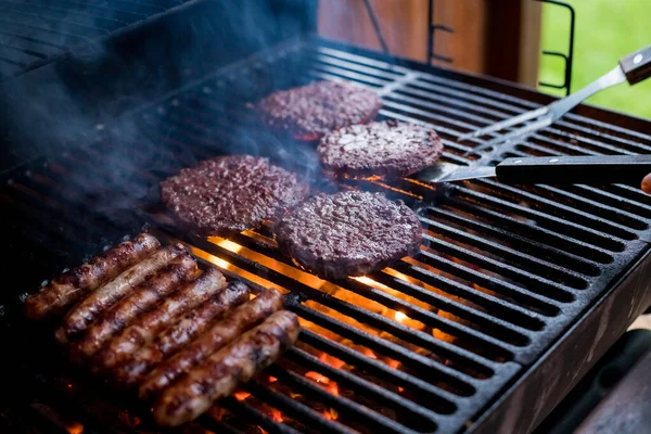 Dymne mięso z hamburgerów grillujące hamburgery. Smażyć na otwartym ogniu na grillu - bbq.Burgery i kiełbasy Gotowanie nad płomieniami na grillu. — Zdjęcie stockowe