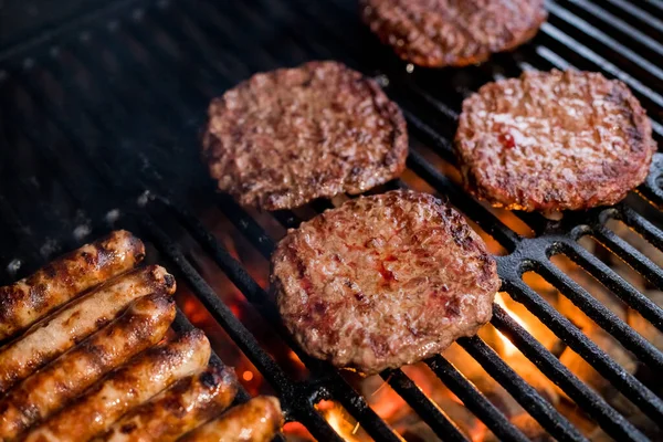 Rauchiges Hamburger-Fleisch-Grillen für Burger. Auf dem Grill am offenen Feuer braten - BBQ. Burger und Würstchen auf dem Grill. lizenzfreie Stockbilder