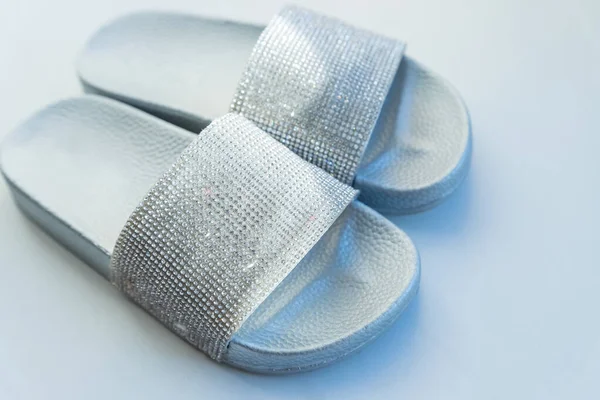 Närbild flickor eller kvinnor ruber glamour mode tofflor står på vit bakgrund. silver flip-flop reglagen. Semester och resor koncept. Upphovsrätt — Stockfoto