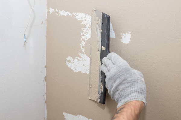 Man plastering wall with putty-knife, preparation for painting.Hands of worker with wall plastering tools renovating house. Plasterer renovating walls and corners with spatula.Copy space