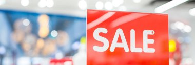 Günlük giyim mağazasının ticaret katındaki kırmızı arka planda beyazla satılan bir tabela. Moda konsepti, indirim sezonu, Kara Cuma, çevrimdışı alışveriş, web afişi.